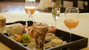 Un plateau avec des boissons et des en-cas dans une chambre d’hôtel, avec un lit et une fenêtre.