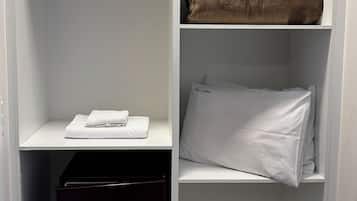 Un armario vestidor con estantes abiertos, una barra para colgar ropa y un mueble de almacenaje negro.