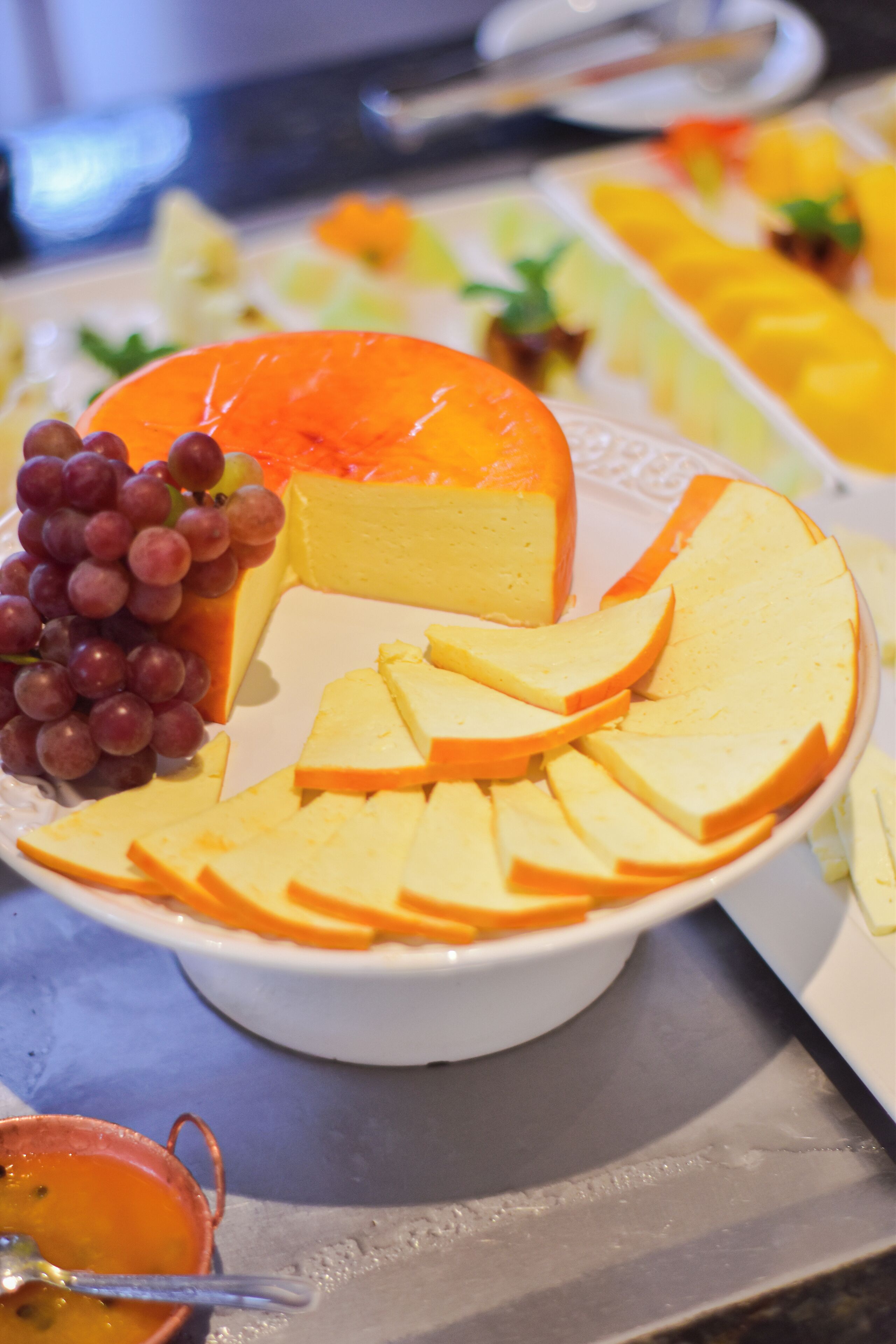 A cheese platter with various cheeses and fruits.