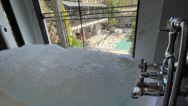 Una bañera con vistas a una piscina y edificios cercanos.