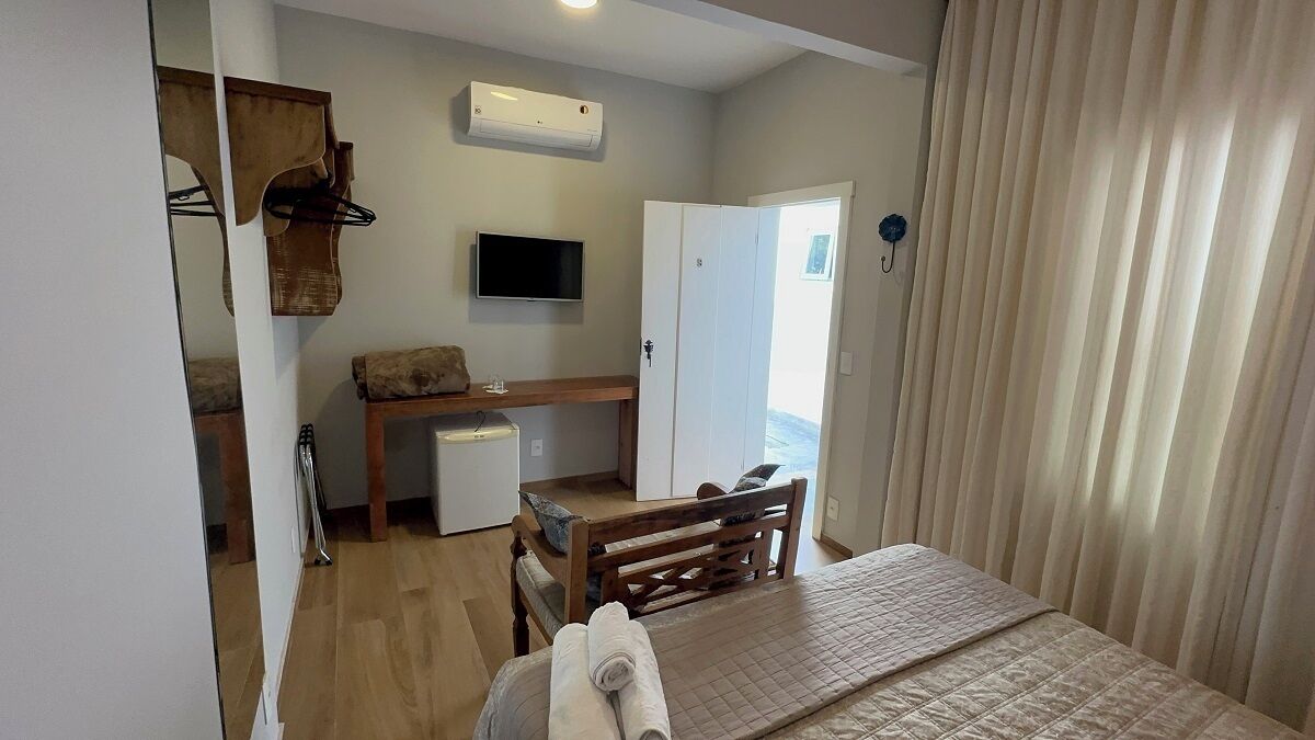 Una camera d'albergo con un letto, una scrivania, una televisione e un armadio.