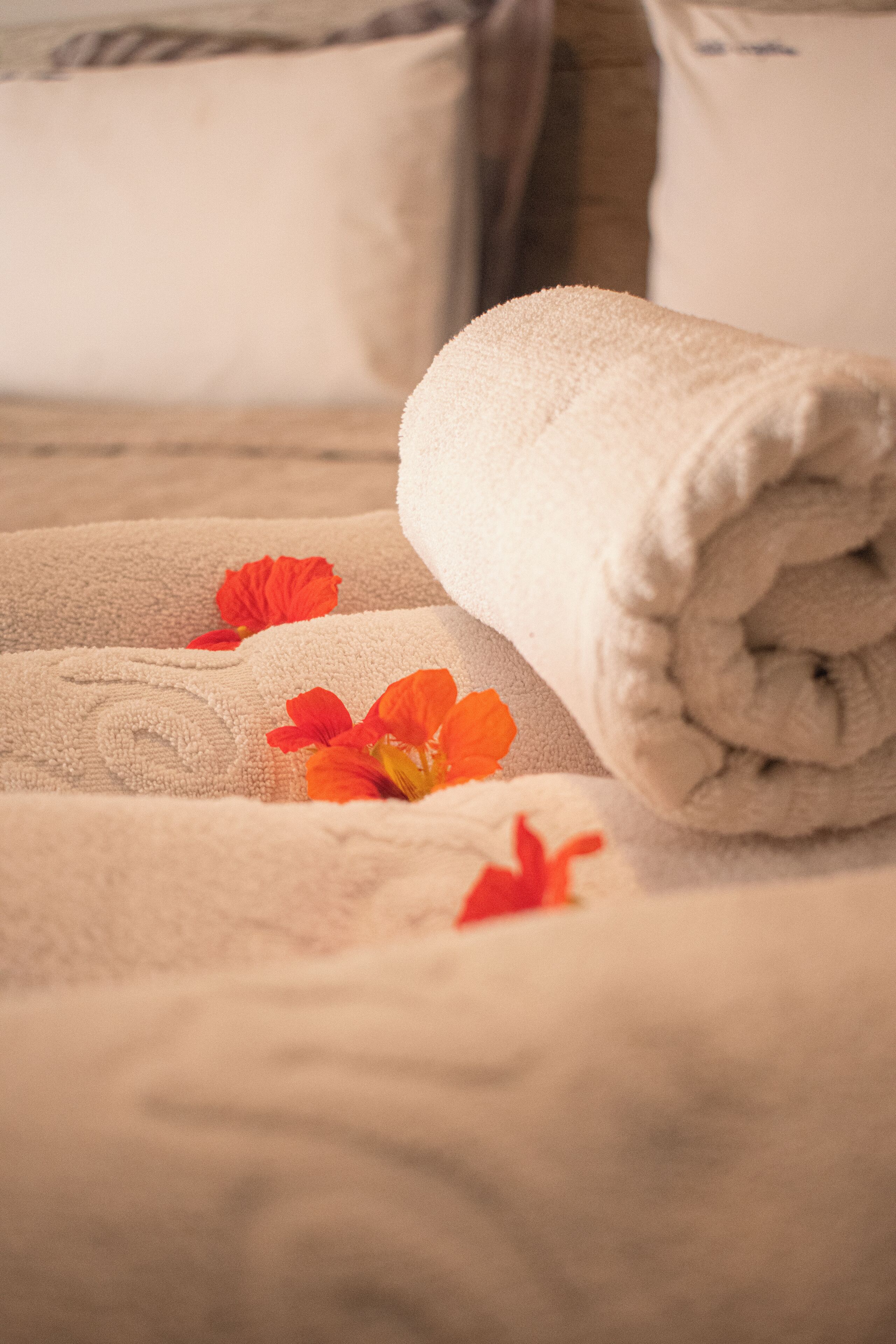 A neatly folded beige towel with a floral pattern on a bed.