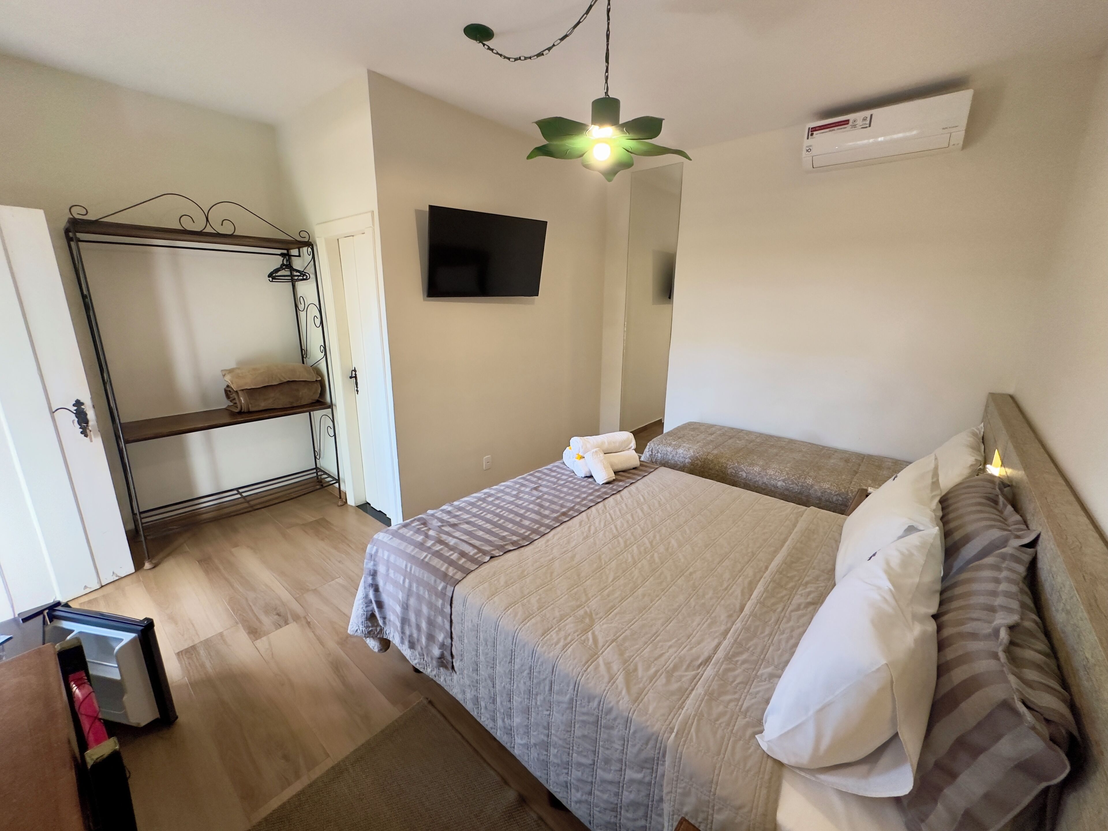A bedroom with two beds, a wardrobe, a TV, and a ceiling fan.