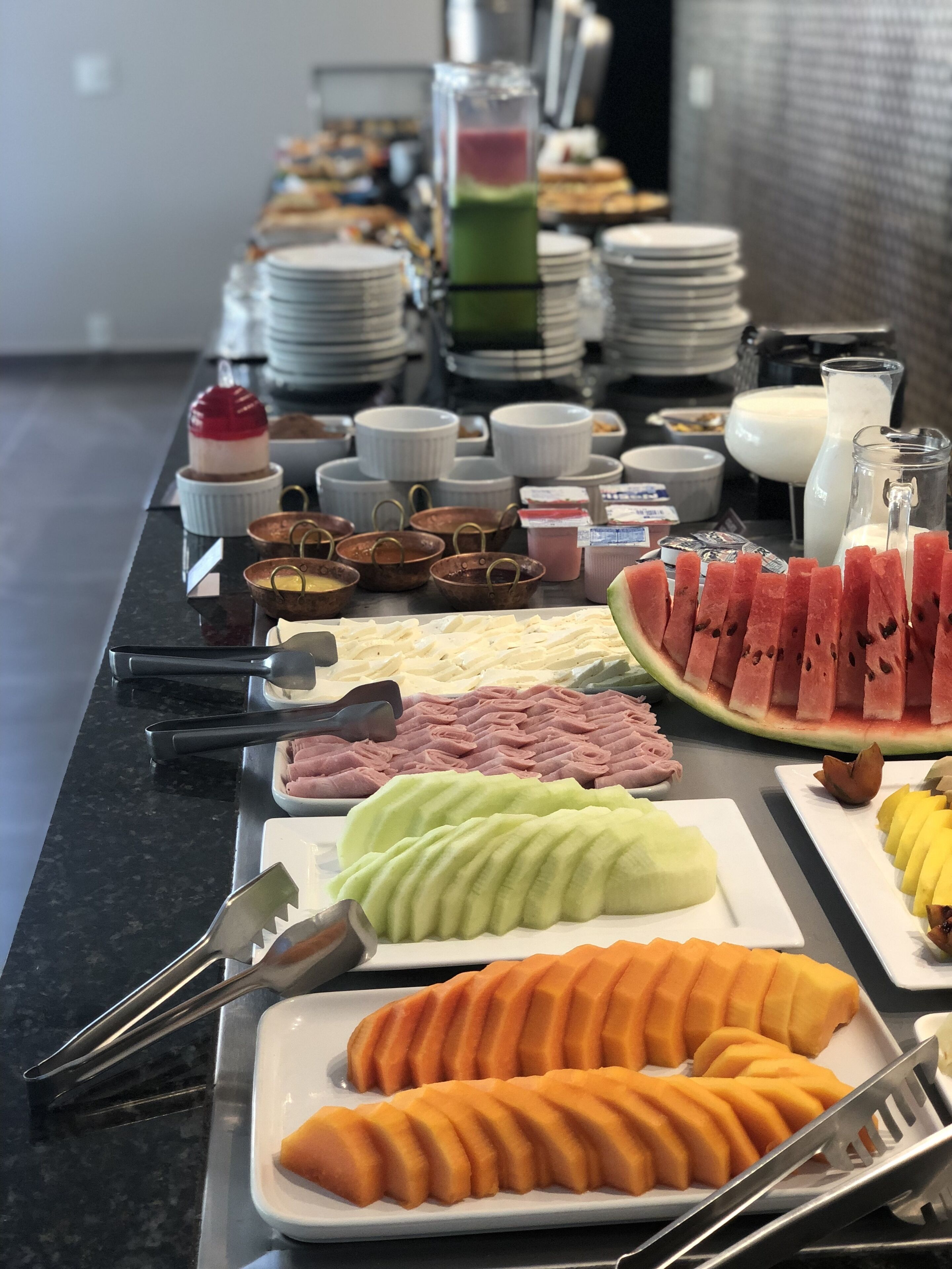 A buffet with various food items including sliced fruits, vegetables, and desserts.