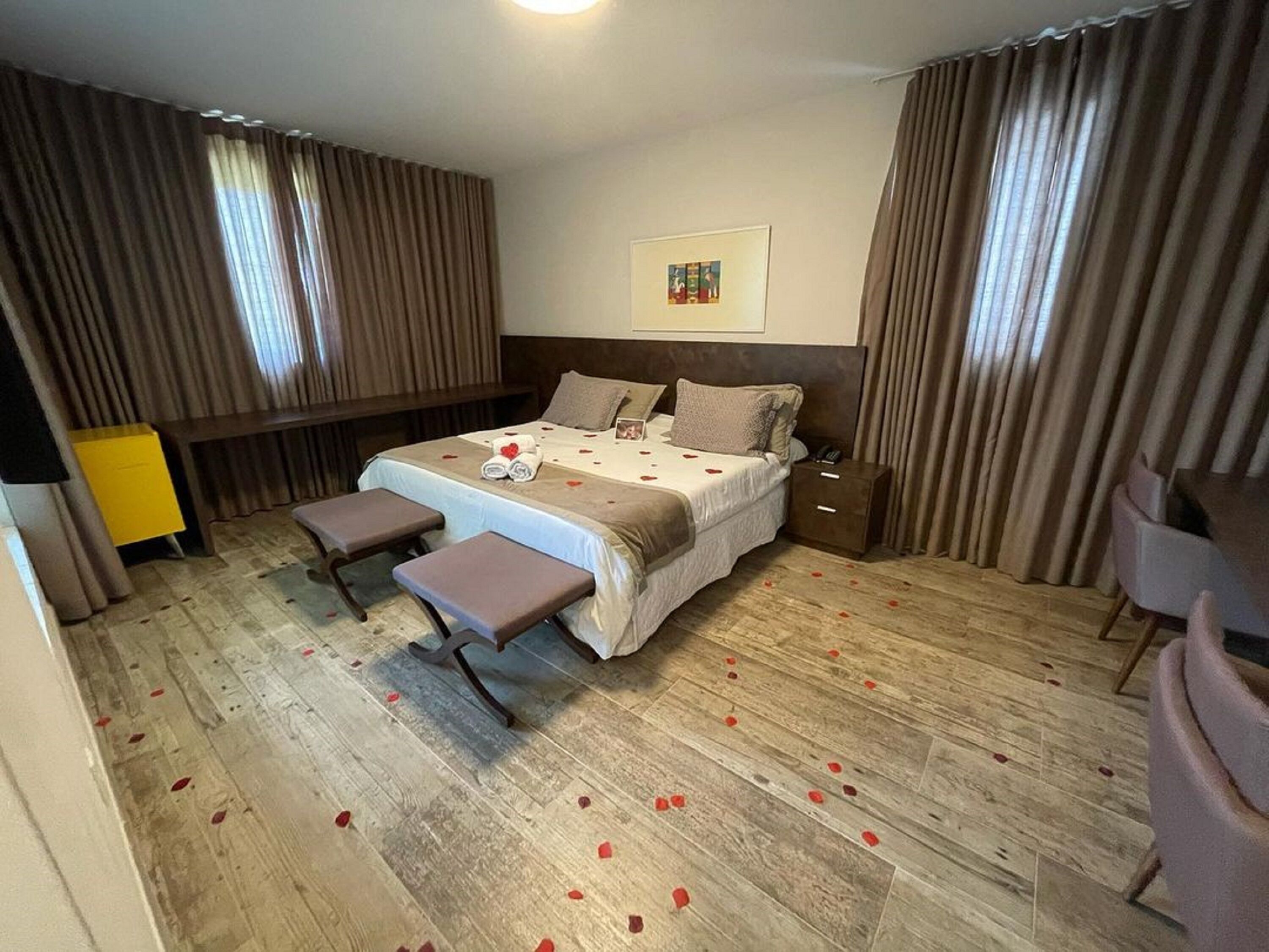 Ein Hotelzimmer mit einem Bett, zwei Nachttischen, einer Bank, einem Sessel und einem kleinen Tisch mit einer Lampe.
