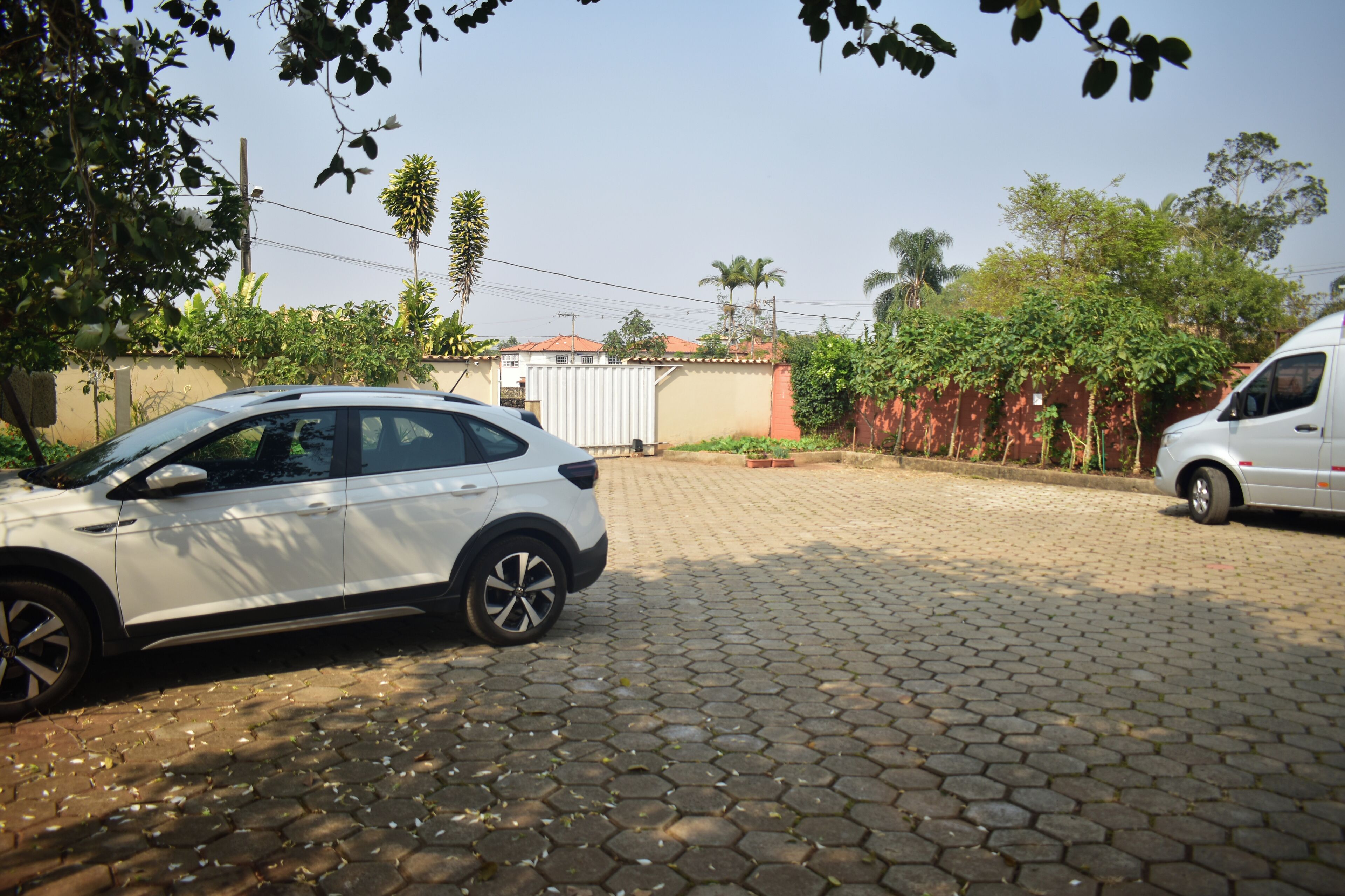 A paved driveway with a white car parked on the left and a white van on the right.