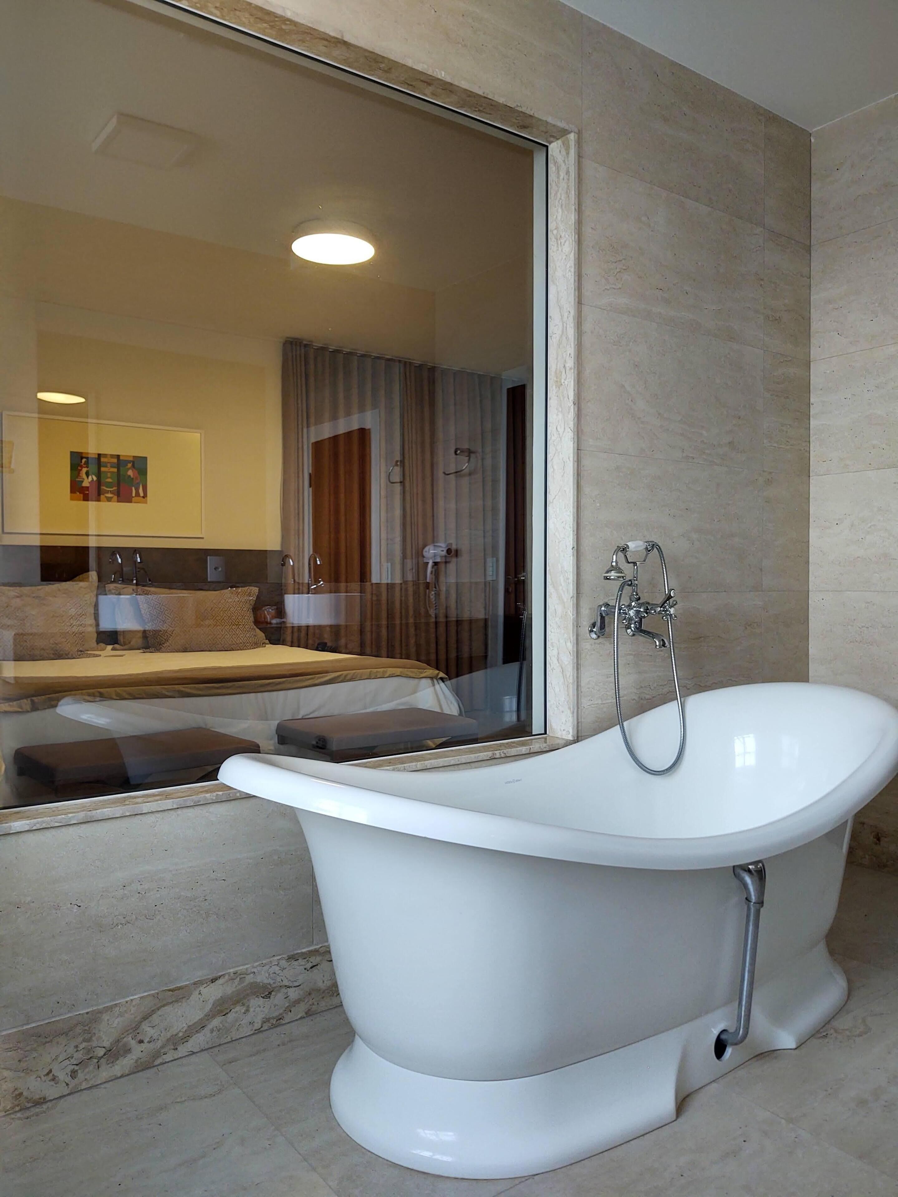 A modern bathroom with a freestanding bathtub, a glass shower enclosure, and a large mirror reflecting the room.