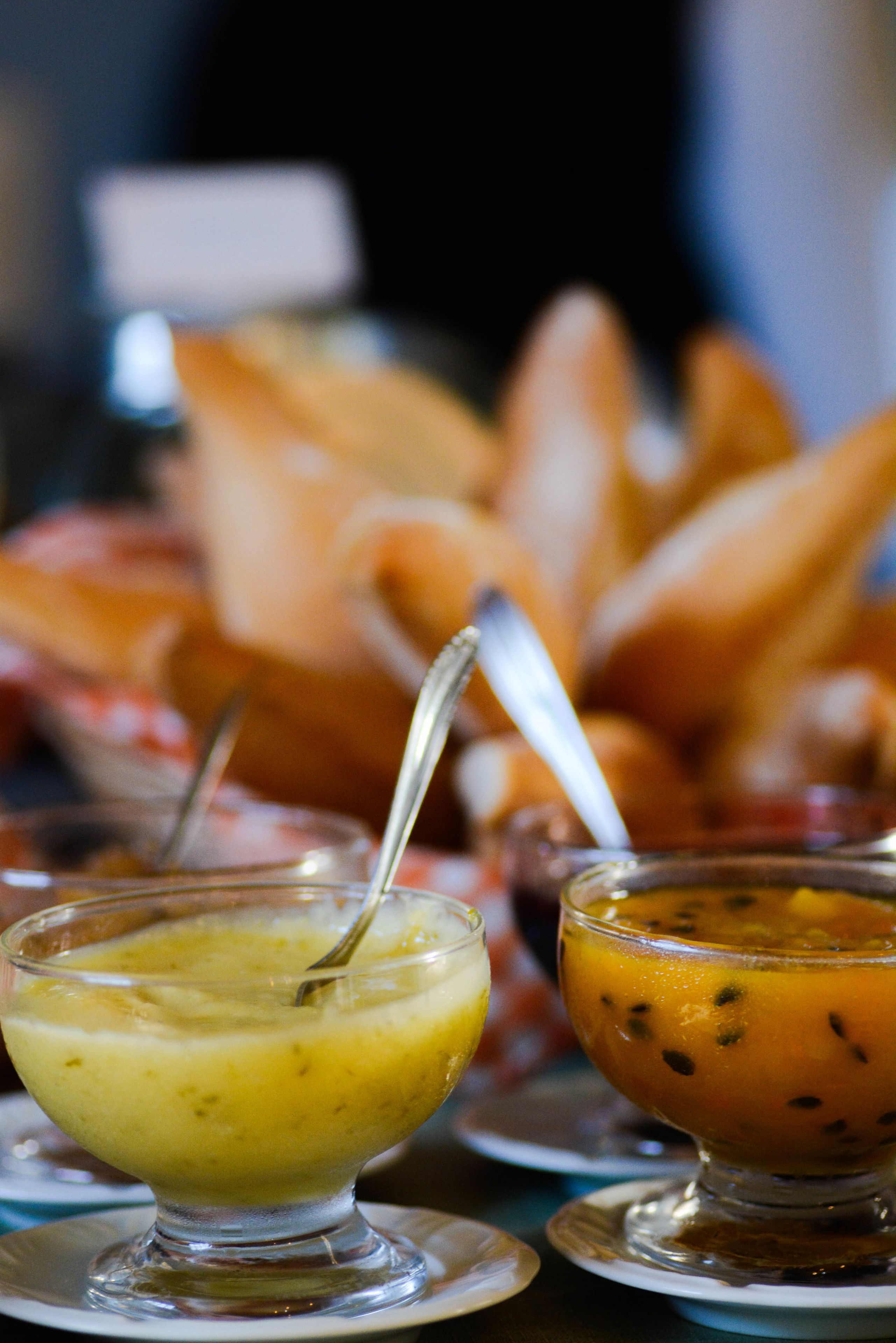 Two bowls of soup on a table with bread in the background.