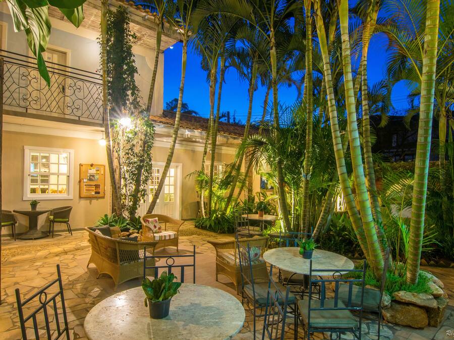A courtyard with outdoor seating, palm trees, and a building with a balcony.
