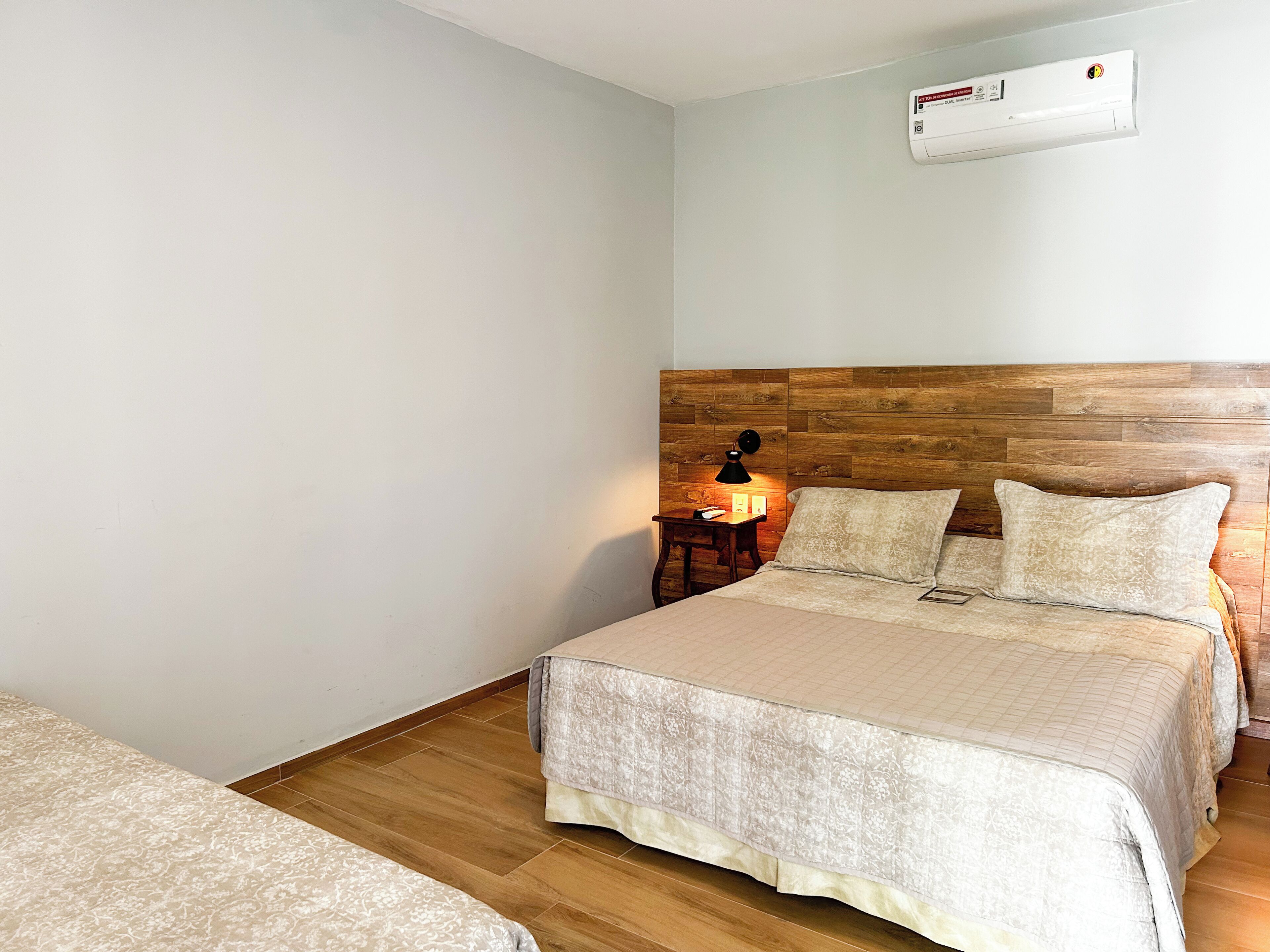 A bedroom with a wooden headboard, a bedside table with a lamp, and a bed with patterned bedding.