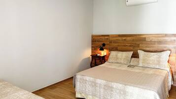 A bedroom with a wooden headboard, a bedside table with a lamp, and a bed with patterned bedding.