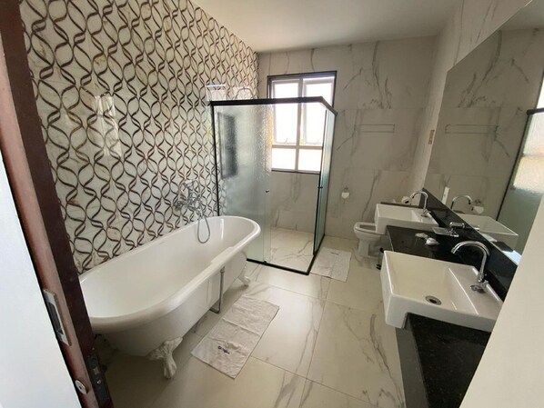 Un baño moderno con una bañera independiente, cabina de ducha de vidrio y tocador con encimera negra.