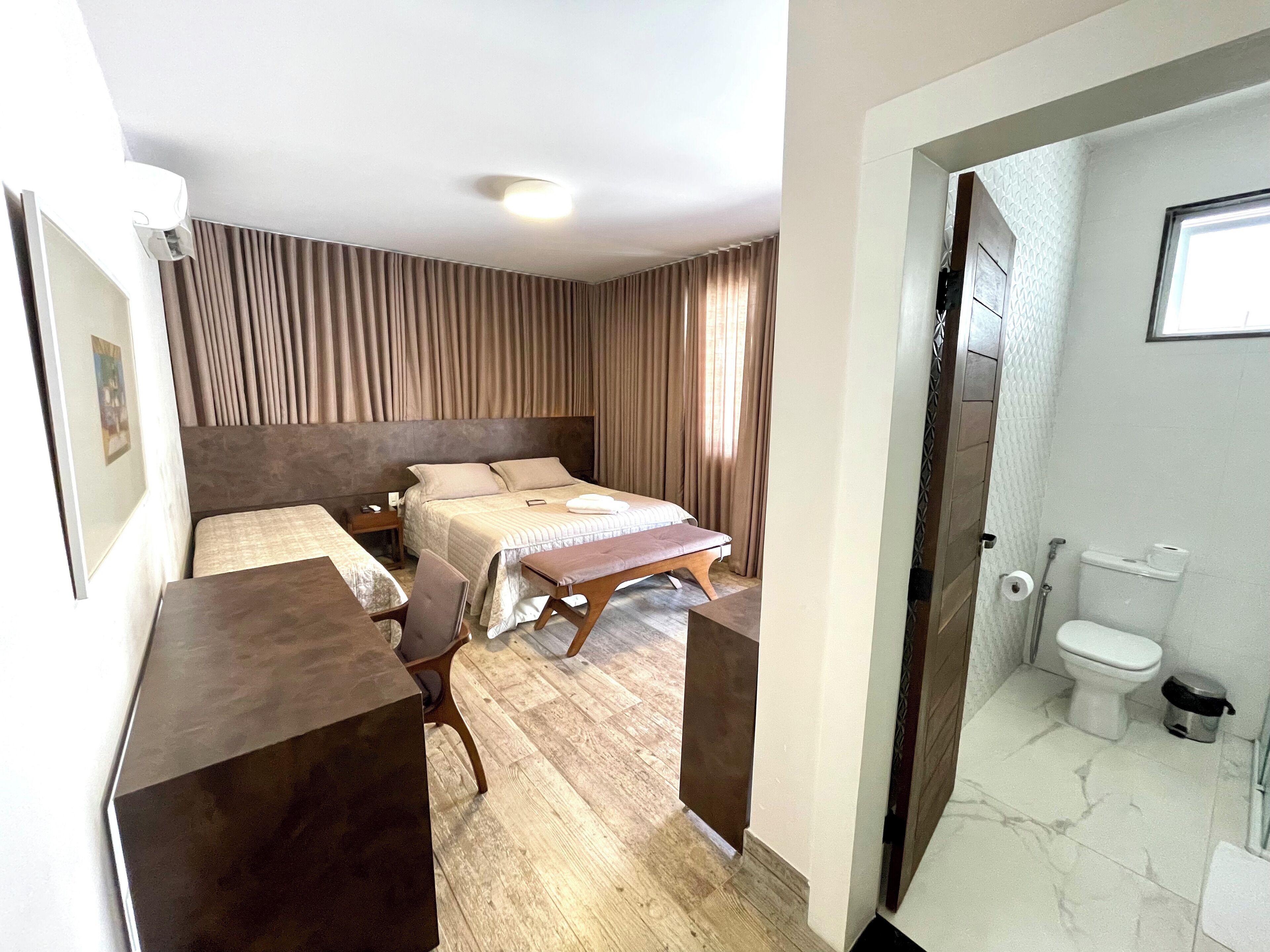 A hotel room with a bed, a desk, and a bathroom.