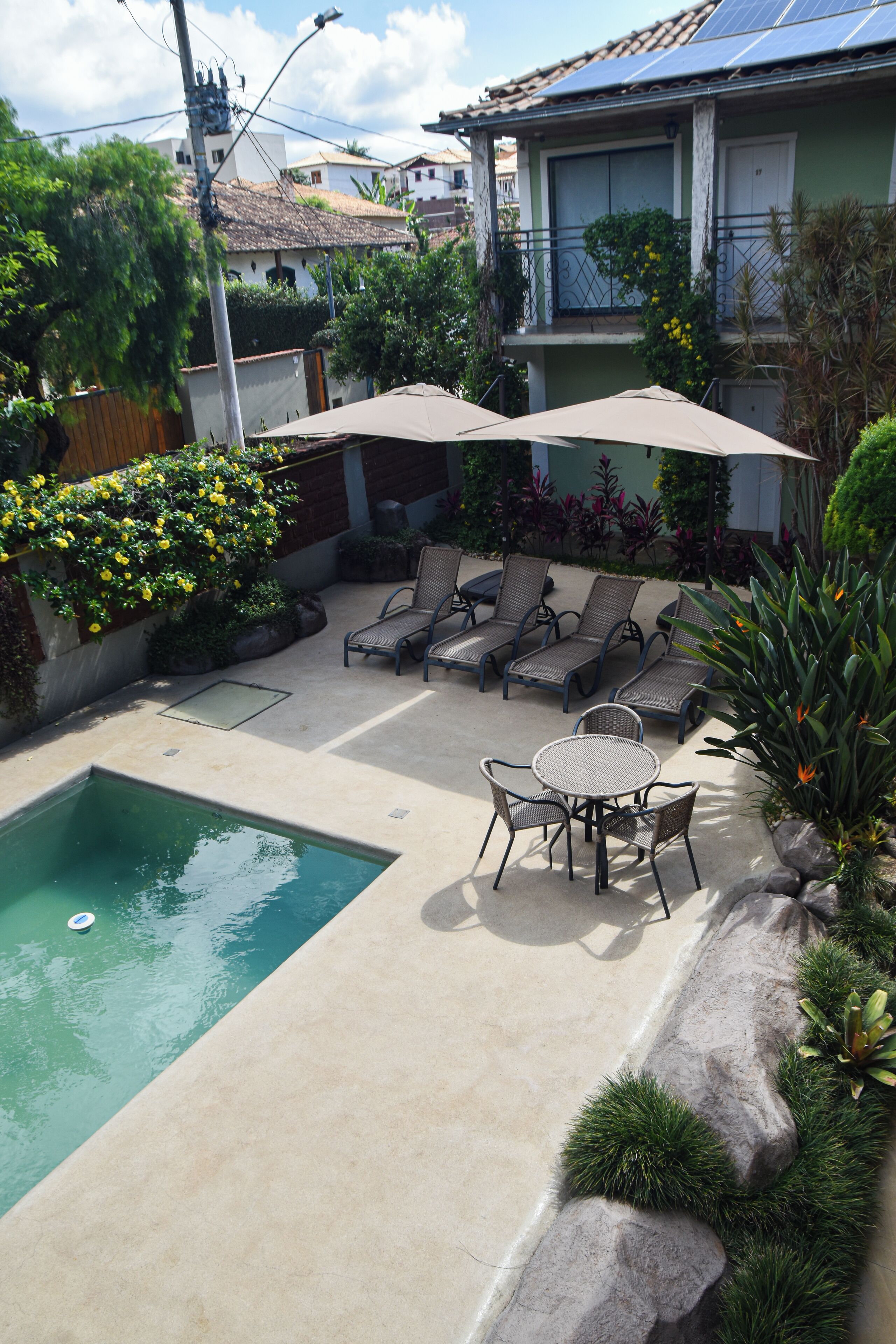 A backyard with a swimming pool, lounge chairs, and umbrellas.