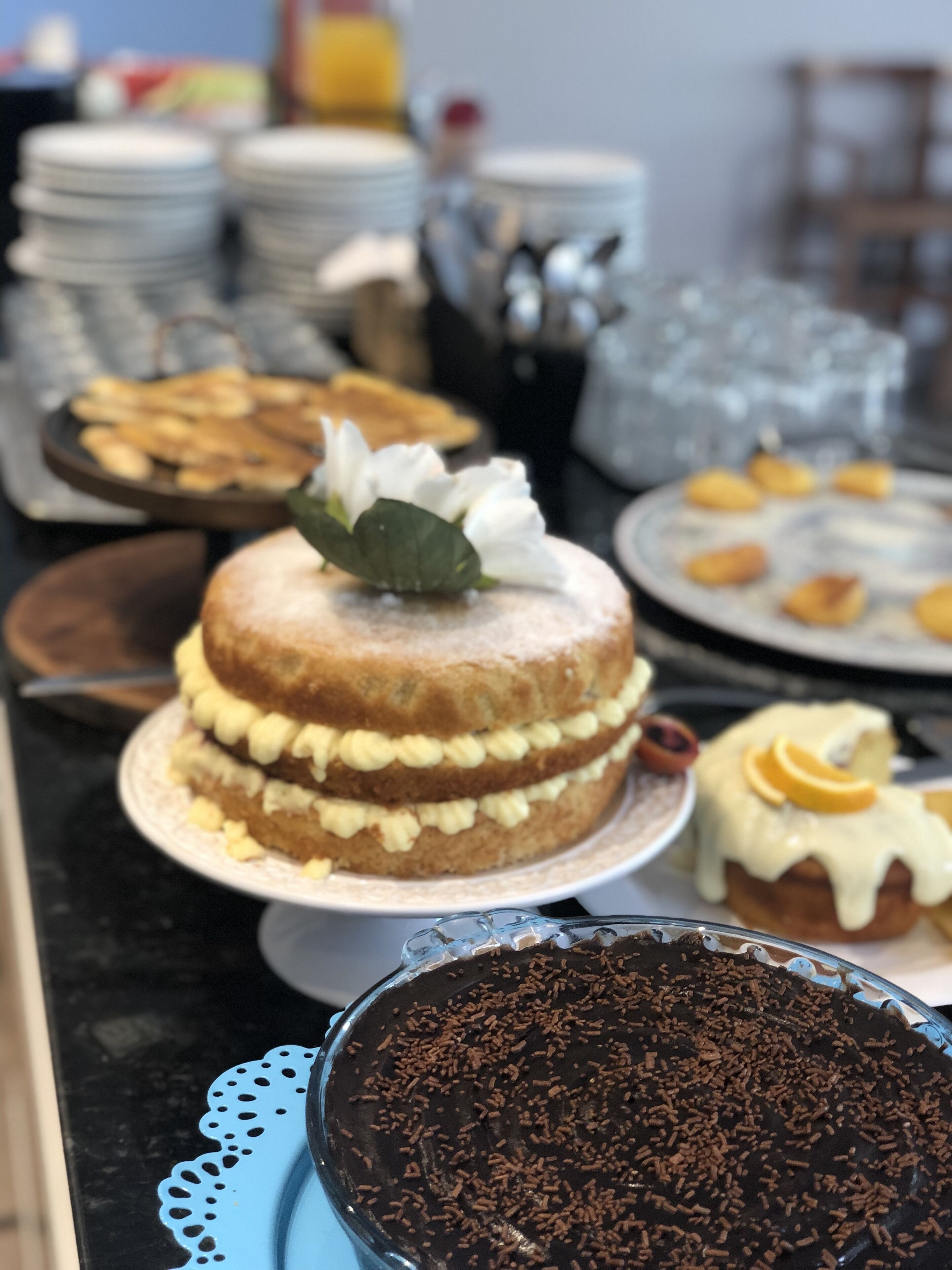 A buffet table with various desserts including a layered cake, pastries, and a chocolate cake with sprinkles.