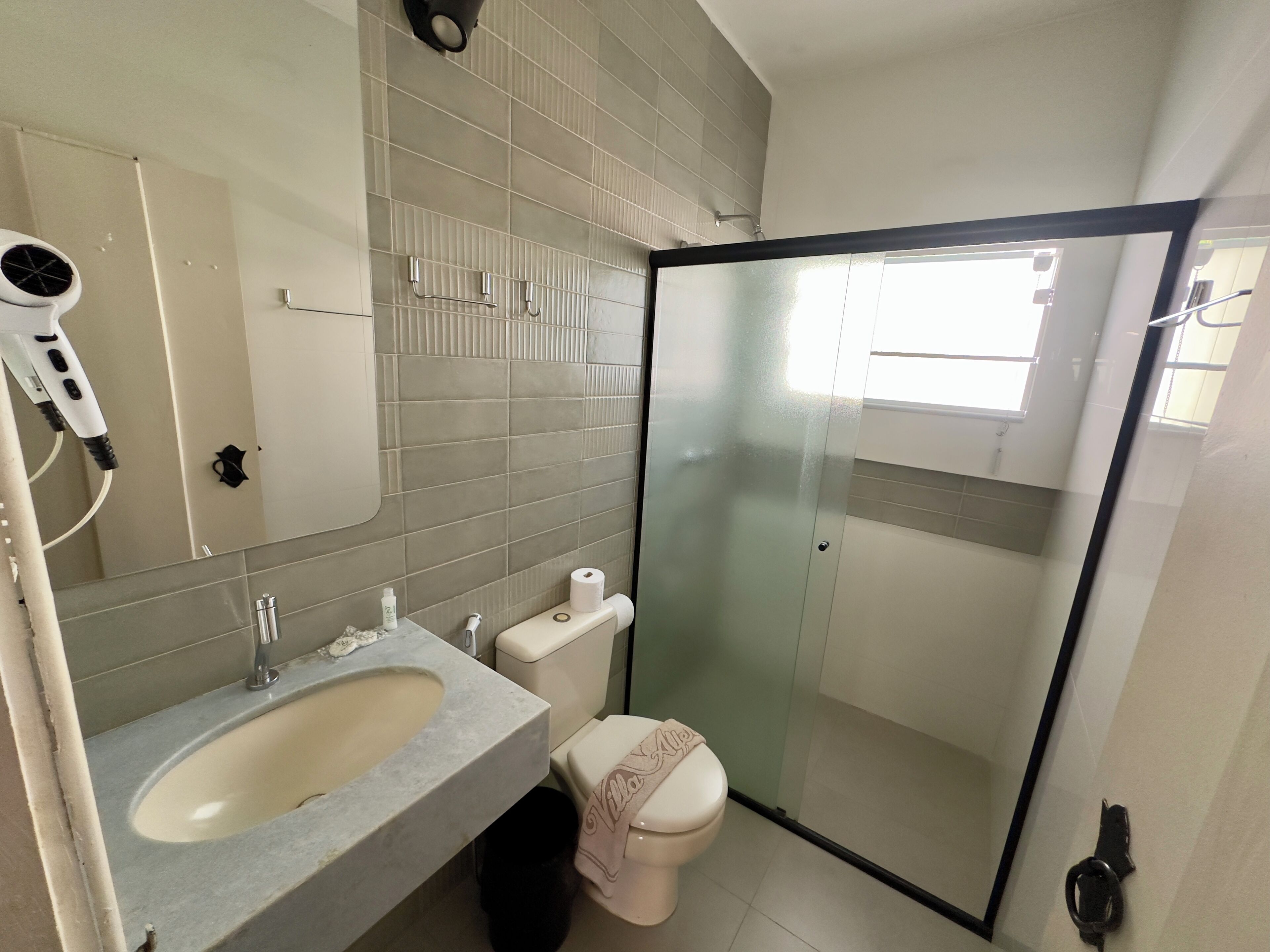 Een badkamer met een wastafel, spiegel, toilet en een douchecabine van glas.