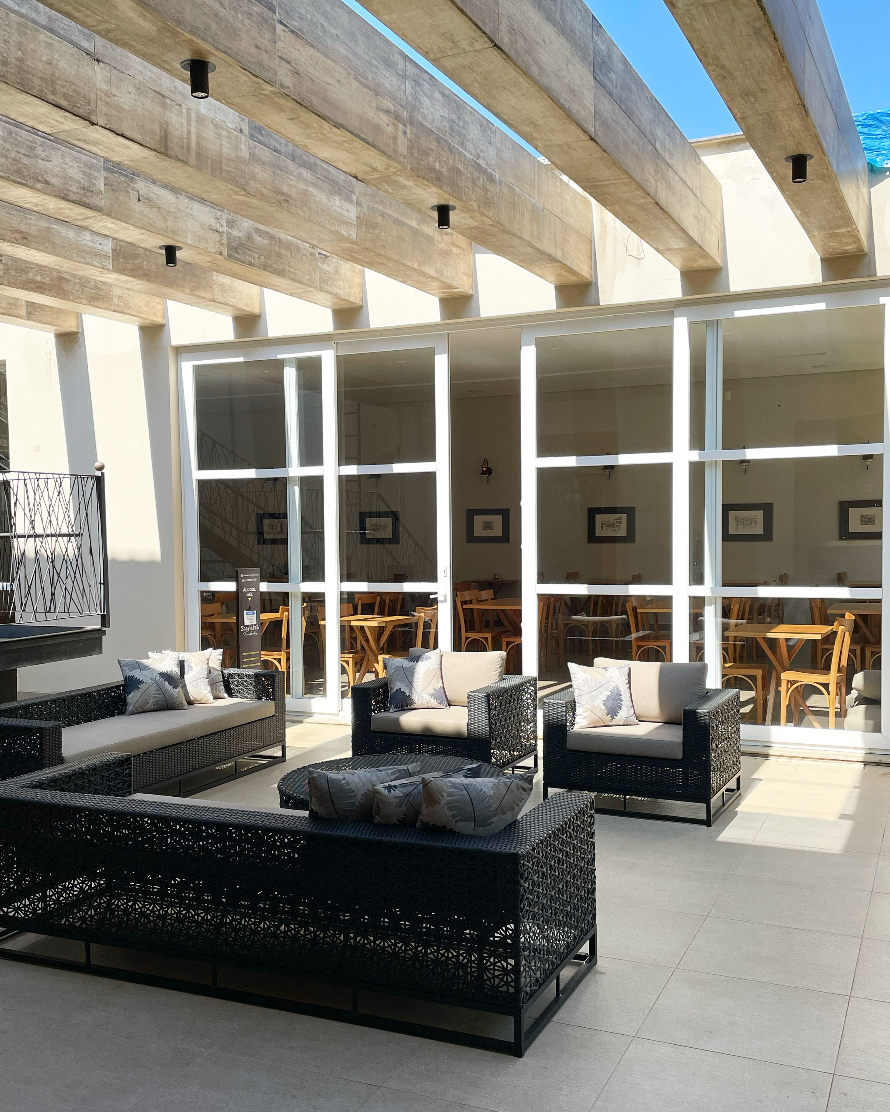 An outdoor seating area with wicker furniture and a glass wall overlooking a dining area.