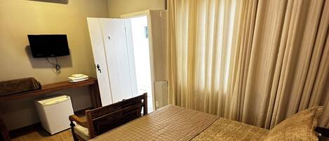 A bedroom with a bed, a TV, a desk, and a wardrobe.