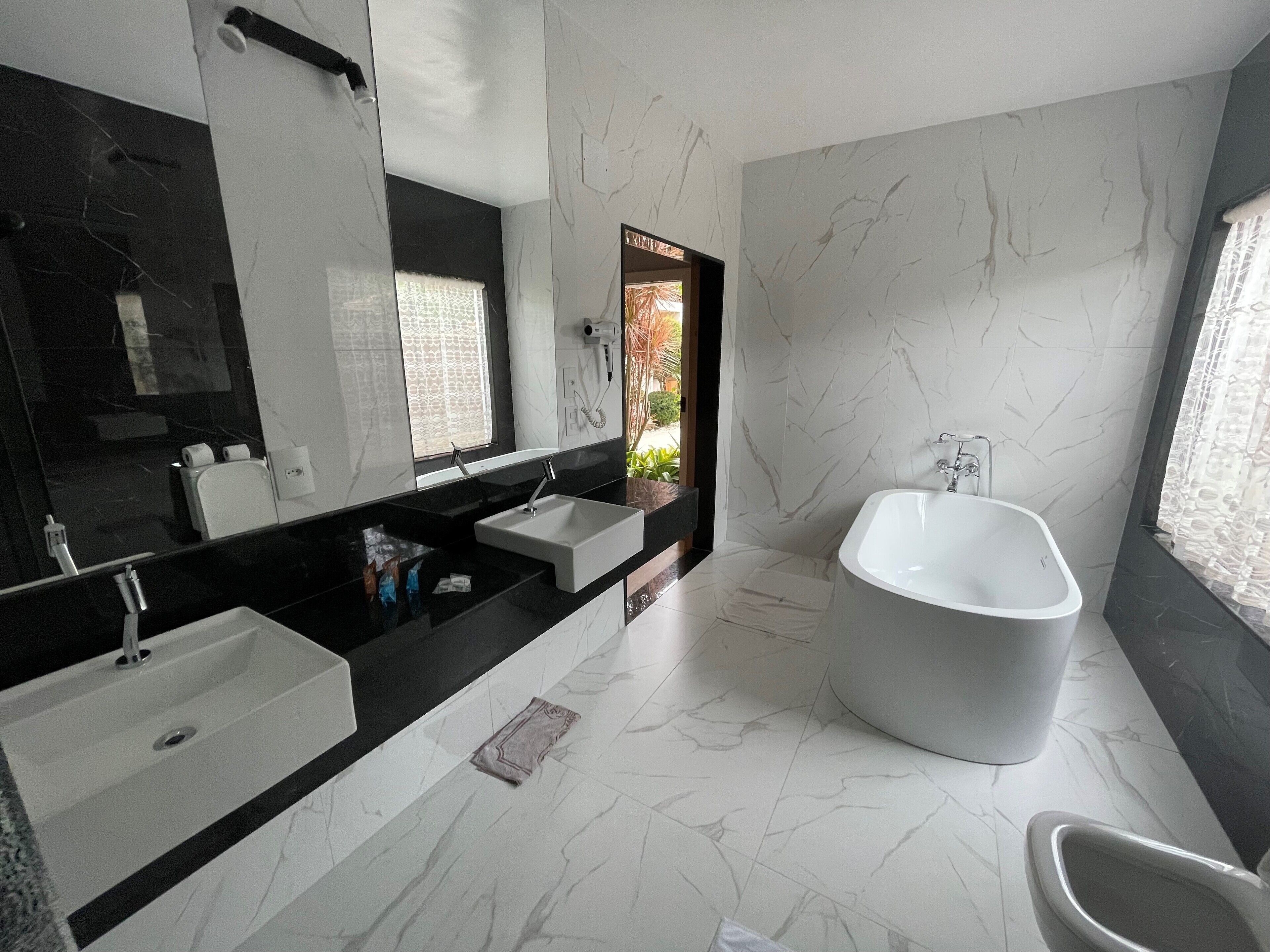 A modern bathroom with a large freestanding bathtub, a double sink vanity, and a large mirror.