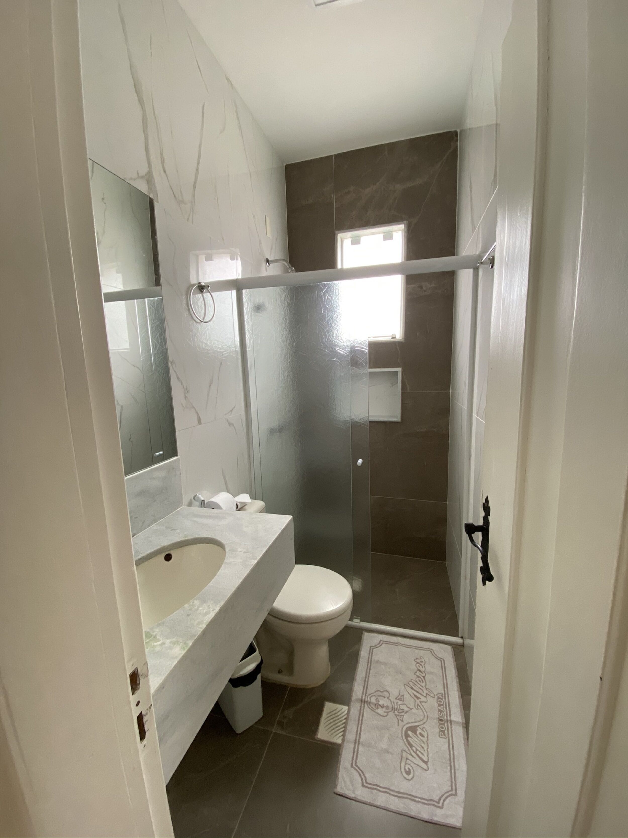 A bathroom with a marble sink, a toilet, and a shower enclosure.
