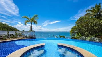 Una piscina al aire libre, sombrillas, sillones reclinables de piscina