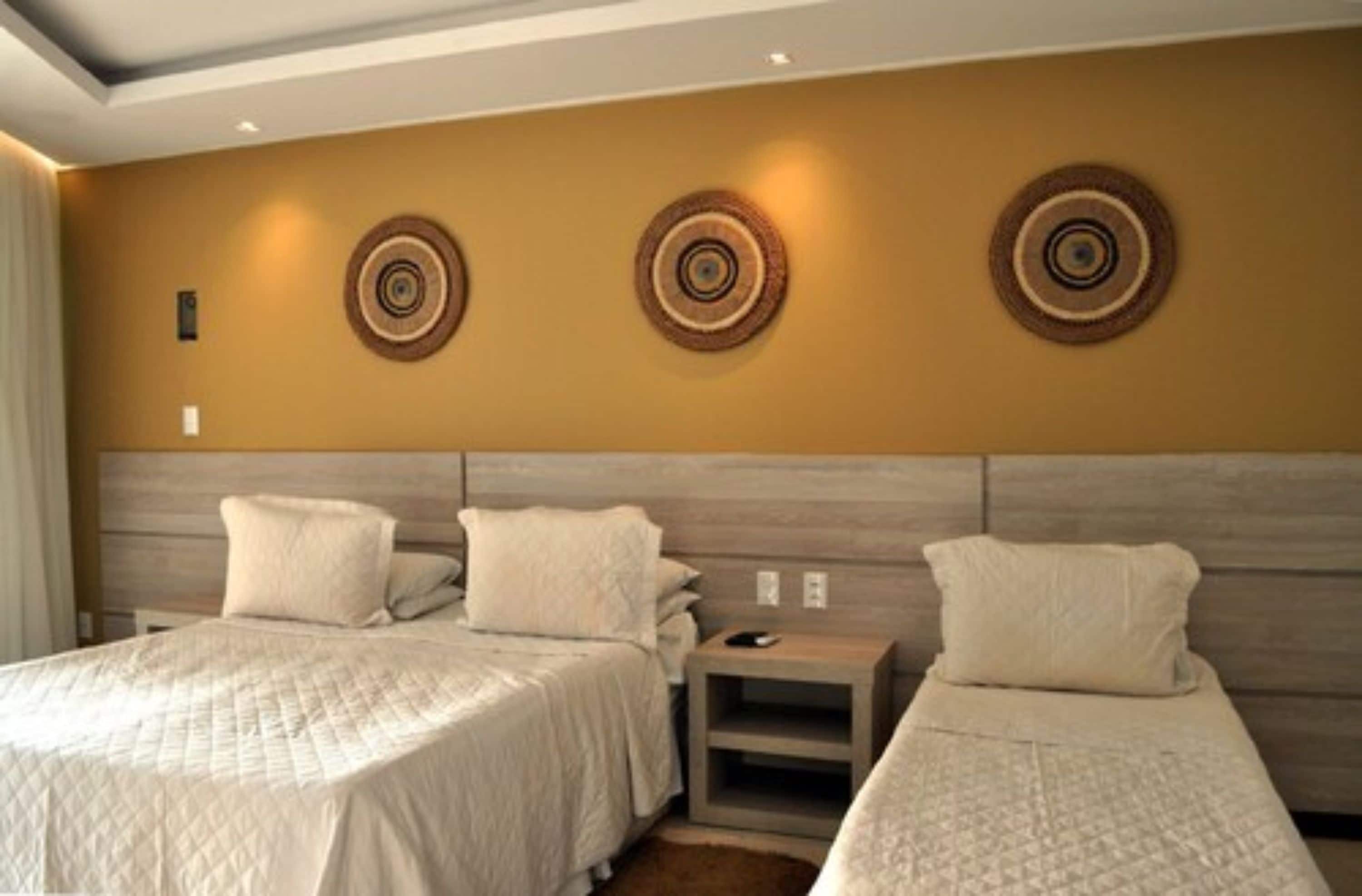 A hotel room with two beds, a wooden headboard, and decorative wall art.