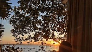 Eine Badewanne mit Blick auf den Sonnenuntergang über dem Meer, eine Topfpflanze und ein Vorhang.