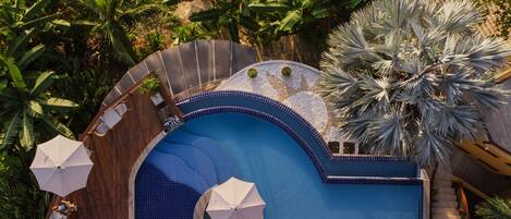 Una piscina al aire libre, sombrillas, tumbonas