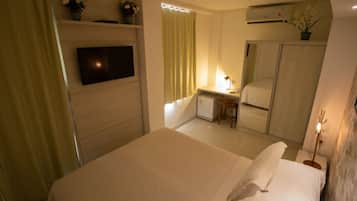 A hotel room with a bed, a desk, a television, a mirror, and a wardrobe.