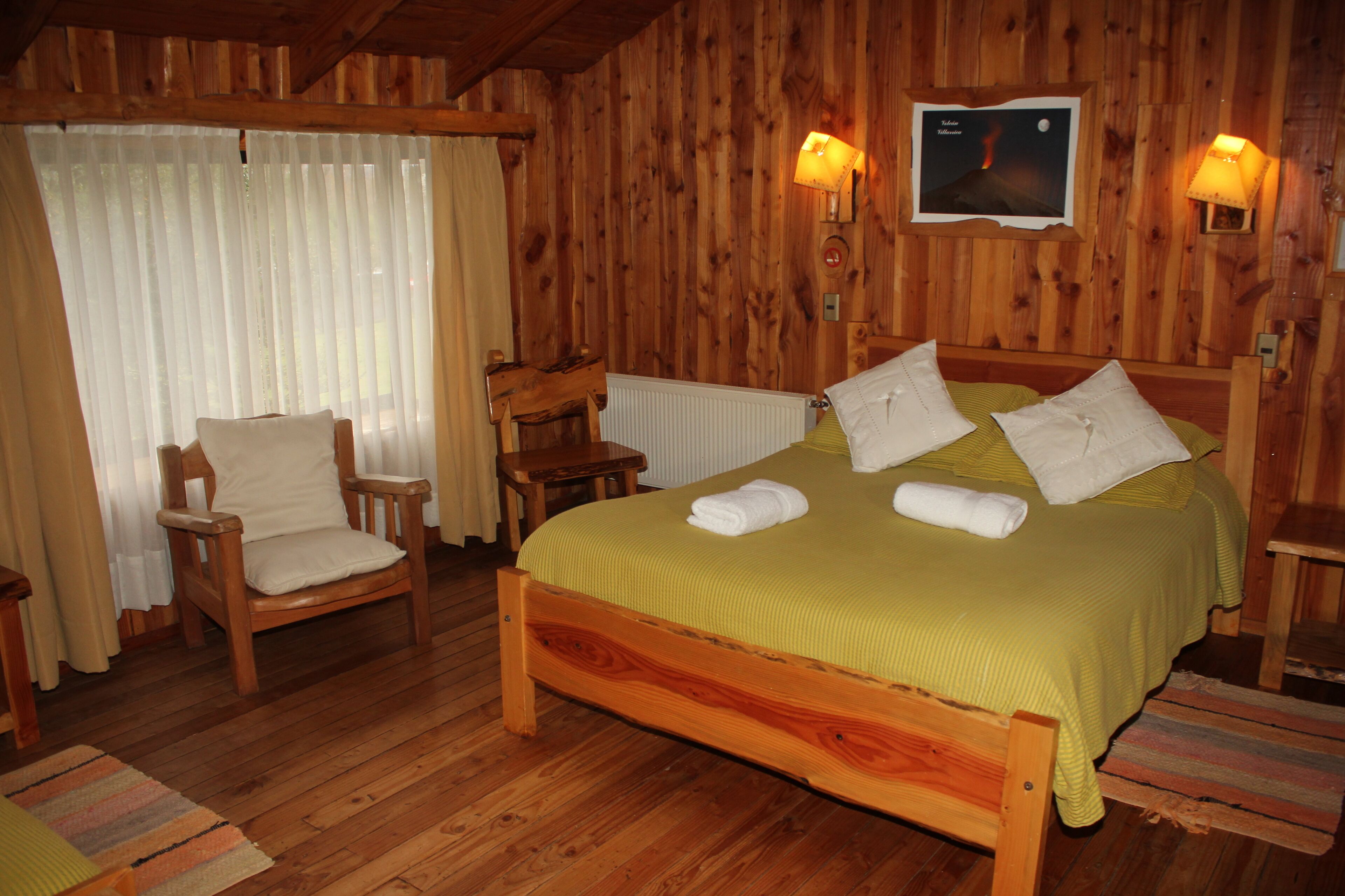 A wooden-paneled room with a bed, a chair, and a table.