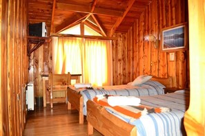A wooden cabin with two beds, a small desk, and a window with curtains. - Hotel Rucapillan (Panguipulli)