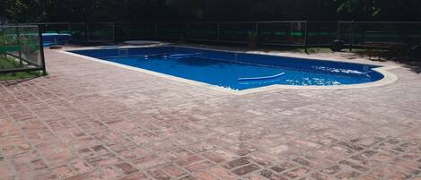 A rectangular swimming pool with a brick patio surrounding it.