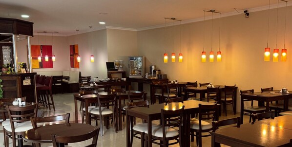 A restaurant with multiple tables and chairs, a bar area, and hanging pendant lights. - Hotel Aire de Patagonia (Rio Gallegos)