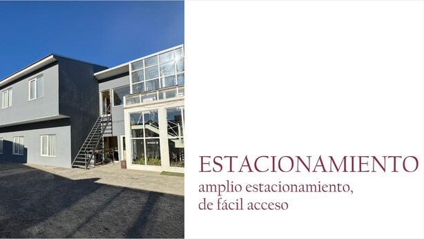 A modern building with a large parking area and a staircase leading to the entrance.