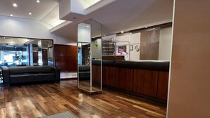 A spacious lobby with wooden flooring, a grey patterned rug, and a seating area with a sofa. - Hotel Torre (Buenos Aires)