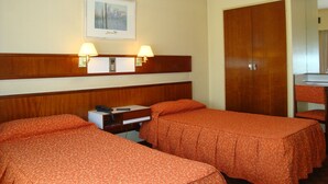 A hotel room with two beds, a wooden headboard, a bedside table with a phone, and a painting on the wall. - Hotel Torre (Buenos Aires)