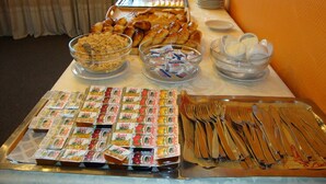 A buffet table with various food items, including pastries, a bowl of cereal, condiments, and utensils. - Hotel Torre (Buenos Aires)