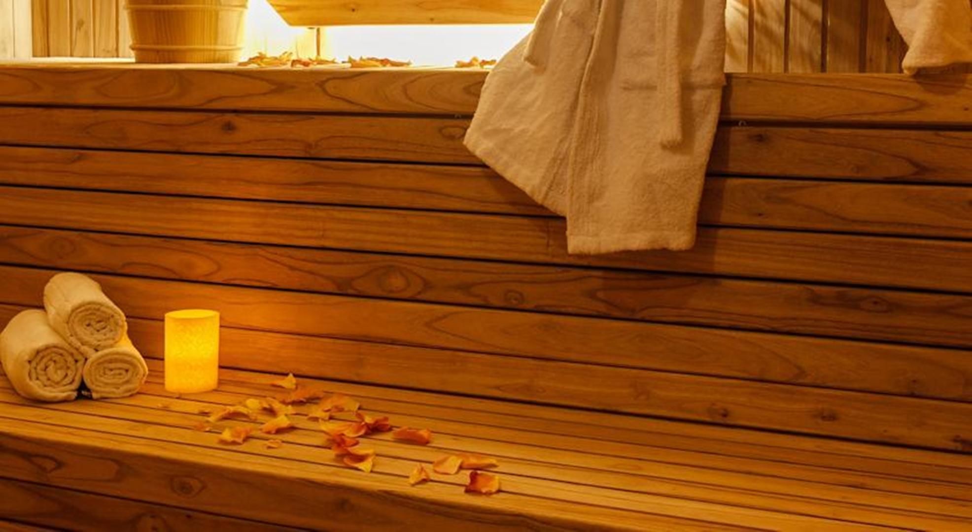 A wooden bench with rolled towels and a candle, suggesting a spa or relaxation area.