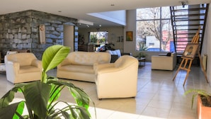 A spacious living area with a stone wall, a large window, and a painting on easel.