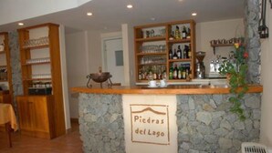 A bar area with a stone counter and shelves of bottles. - Piedras del Lago (Tandil)