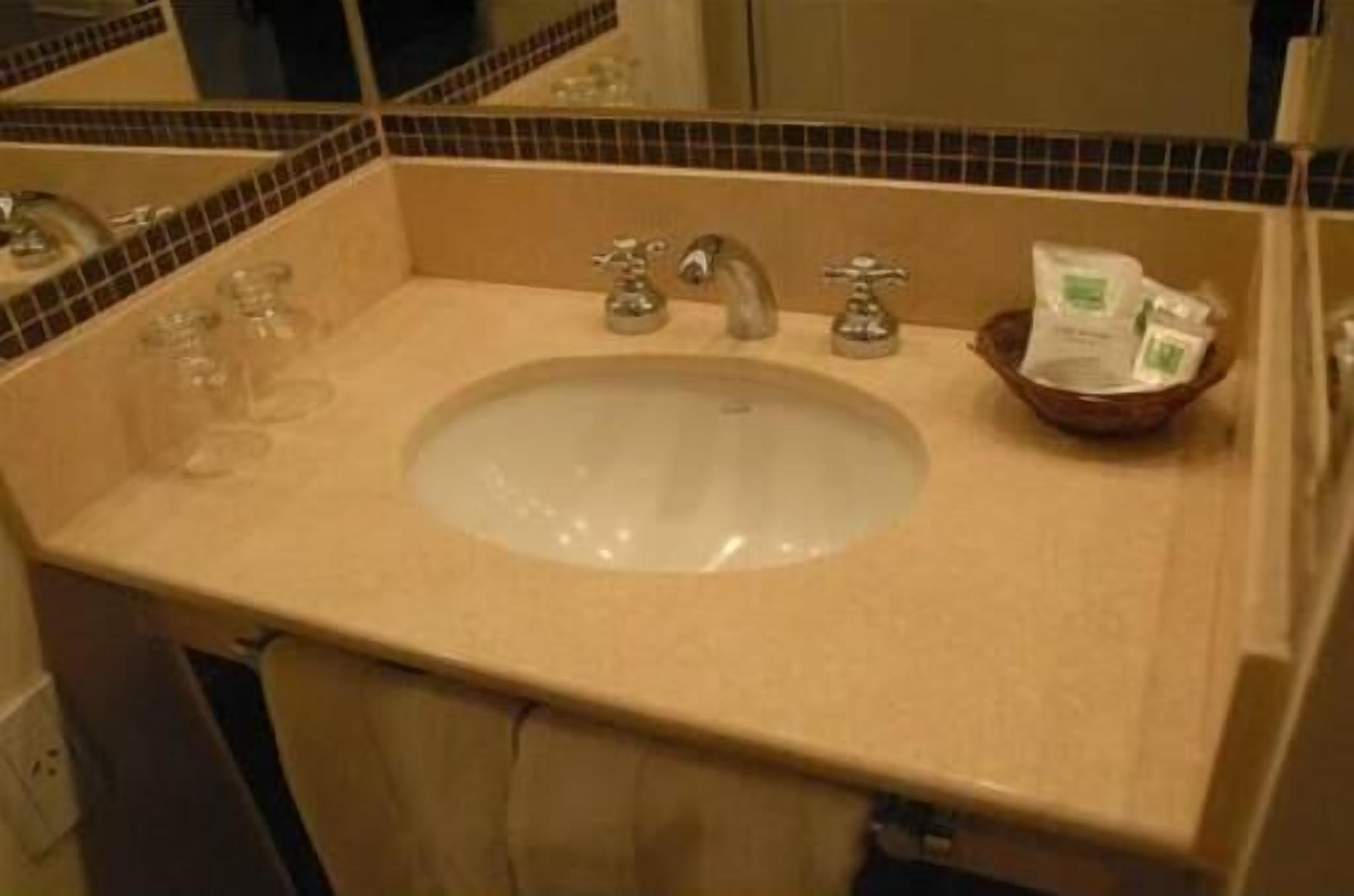 A bathroom sink with a mirror, two faucets, and a soap dish.