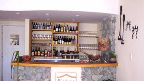 A bar area with shelves of bottles and glasses, a stone counter, and a sign reading "Piedras del Lago". - Piedras del Lago (Tandil)