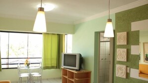 A room with a dining table, chairs, a television on a stand, and artwork on the walls. - Paradise Flat Residence (Caldas Novas)