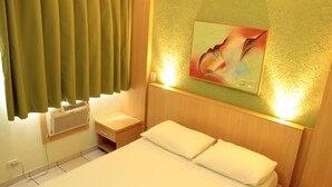 A hotel room with a bed, a bedside table, a wall-mounted heater, and a painting on the wall. - Paradise Flat Residence (Caldas Novas)