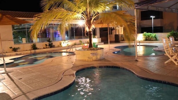 A swimming pool area with palm trees and lounge chairs. - Paradise Flat Residence (Caldas Novas)