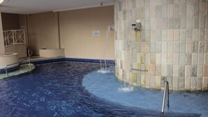 A swimming pool with a stone wall and a tiled floor. - Paradise Flat Residence (Caldas Novas)