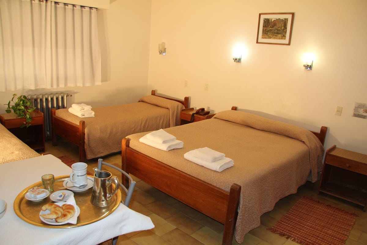 Une chambre d'hôtel avec deux lits, une table à manger avec des aliments pour le petit-déjeuner et un radiateur.
