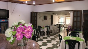 A restaurant with a checkered floor, tables with green and white tablecloths, and chairs. - Hotel Venecia Confort (San Juan de Pasto)