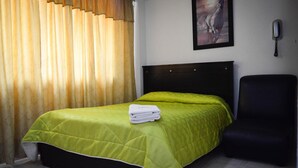 A hotel room with a bed, a chair, a painting on the wall, and a telephone. - Hotel Venecia Confort (San Juan de Pasto)