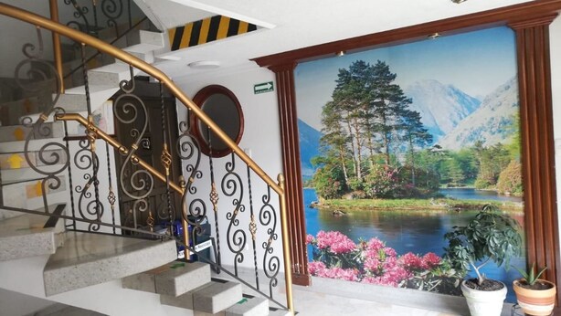 A staircase with ornate metal railings and a scenic mural of a lake and mountains. - Hotel Venecia Confort (San Juan de Pasto)
